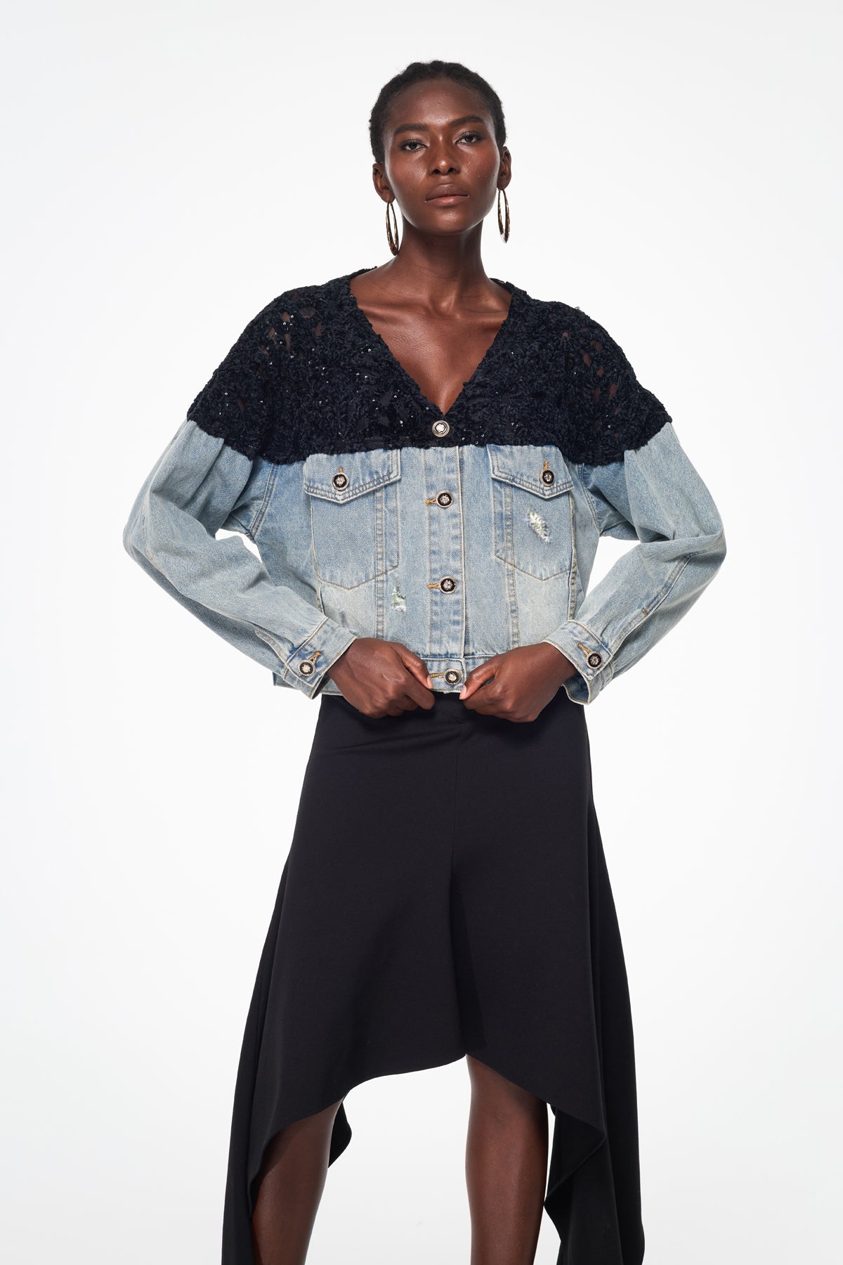 Woman wearing a black top and denim jacket with a white background