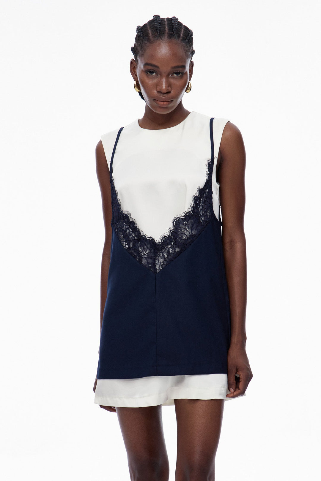 Woman wearing a navy and white dress with lace detail on a white background
