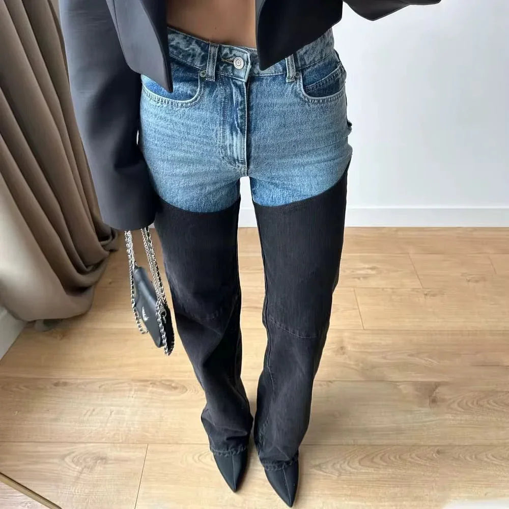 Woman wearing two-tone high-waisted jeans, black blazer, pointed heels, holding chain purse