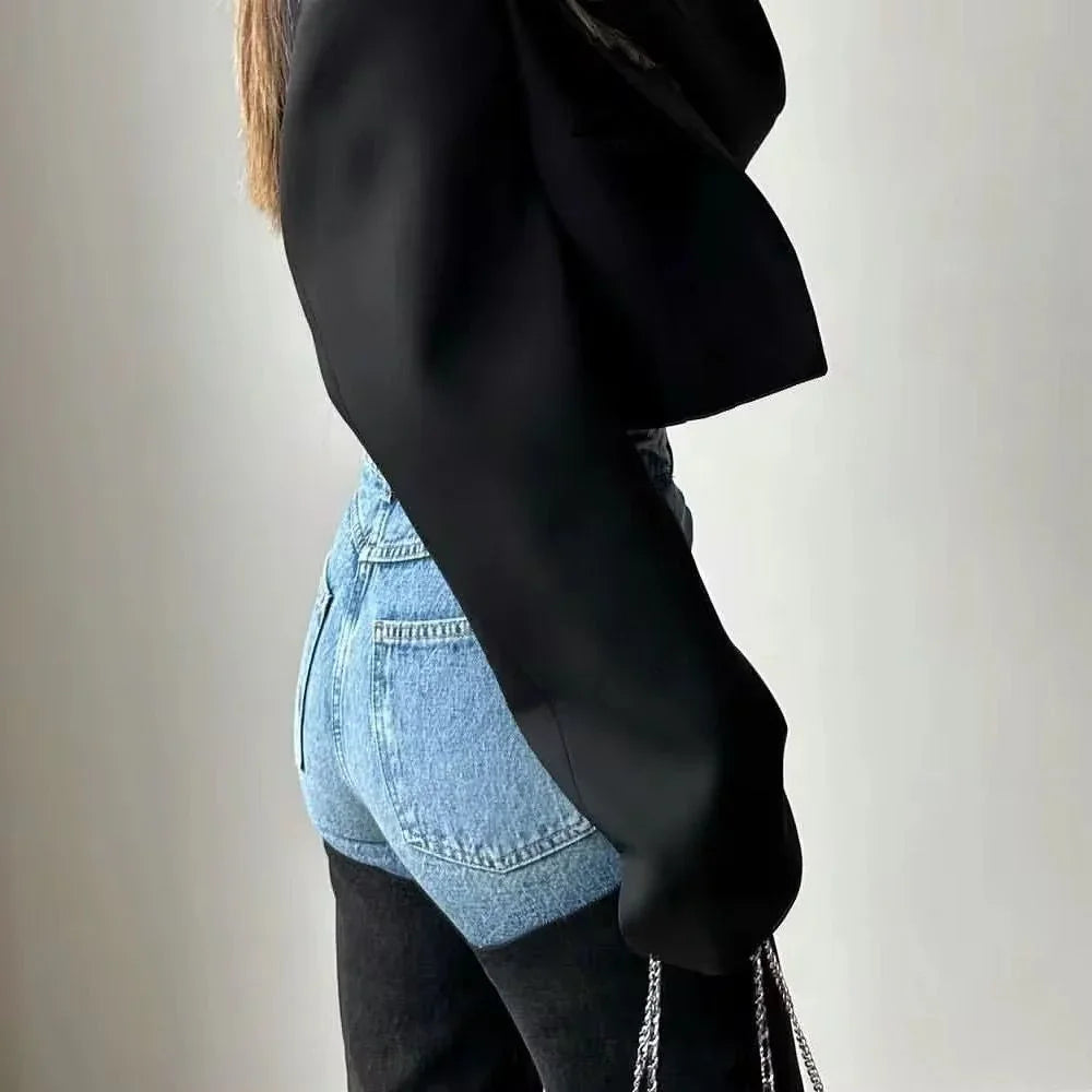Woman wearing high-waisted two-tone denim jeans and a black cropped blazer