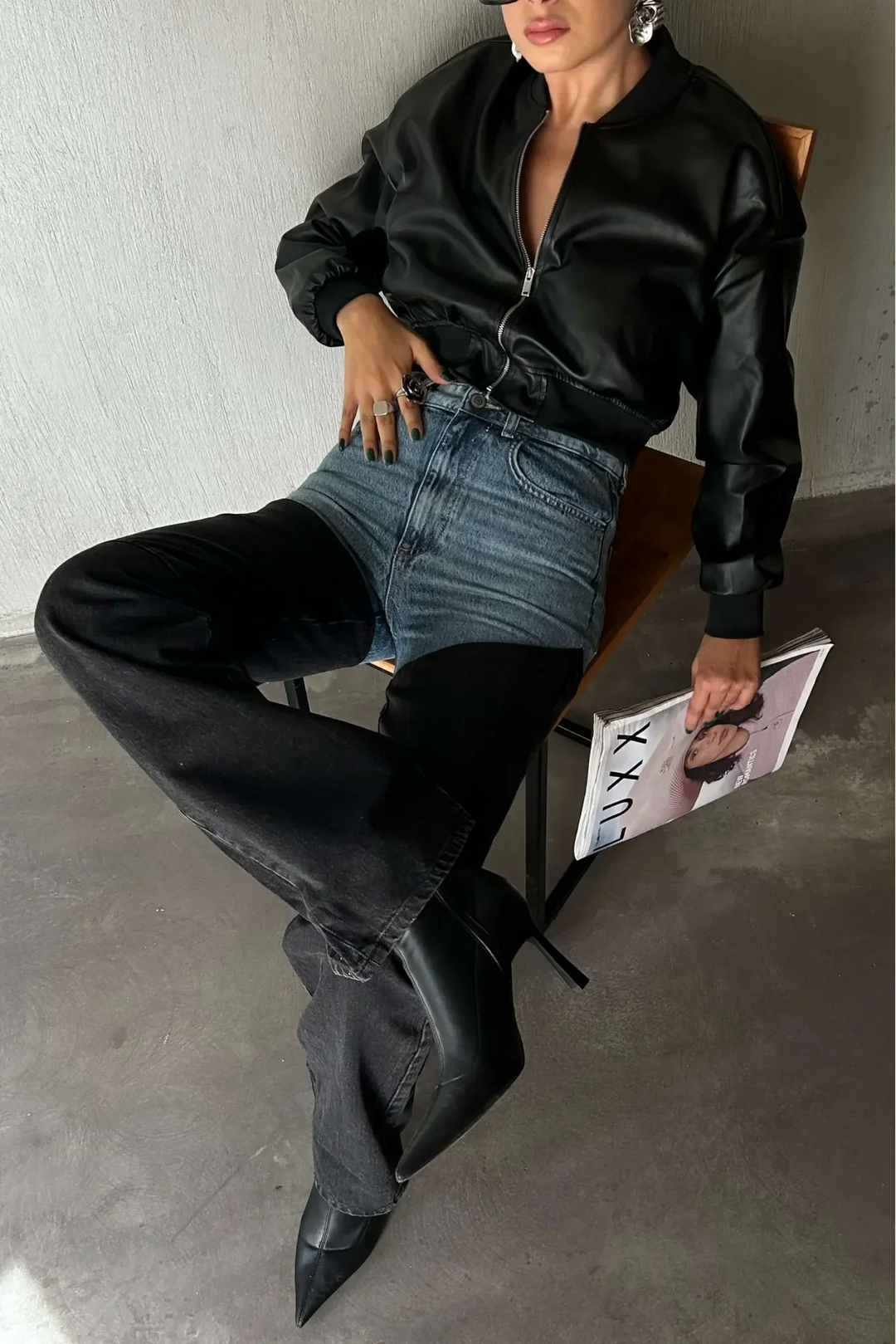 Woman wearing two-tone blue and black wide-leg jeans, black leather jacket, and heeled boots