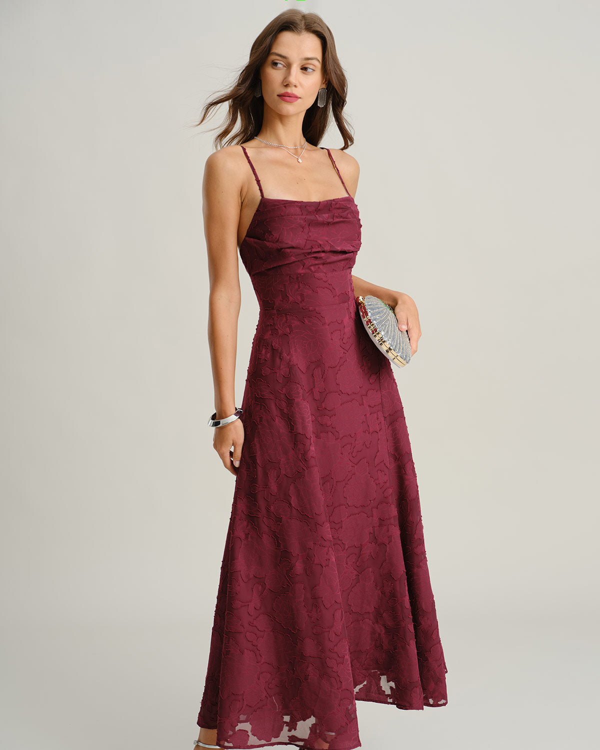 Woman wearing a burgundy lace dress against a plain background